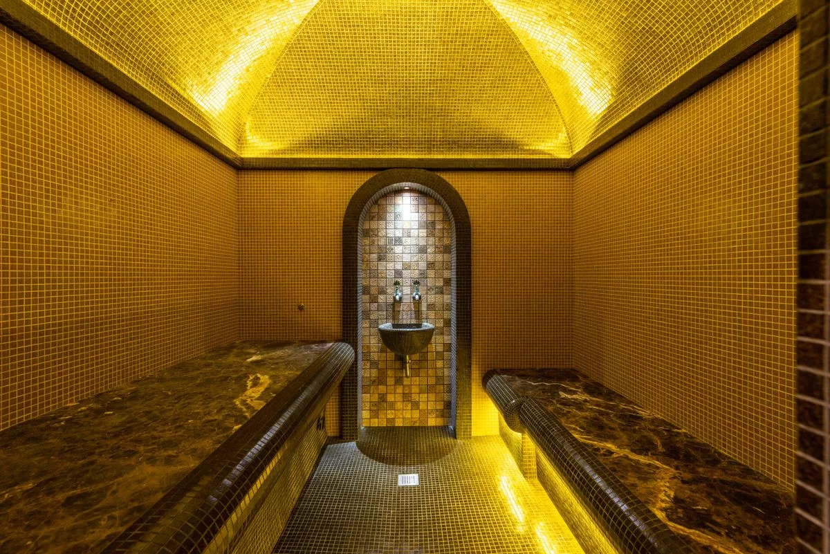 Bagno turco con cupola a mosaico dorato e panche in marmo
