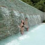 una donna e un uomo in una piscina termale sotto a delle cascate di acqua termale